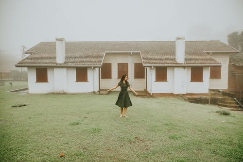 女人站在外面的房子的照片 · 免费素材图片