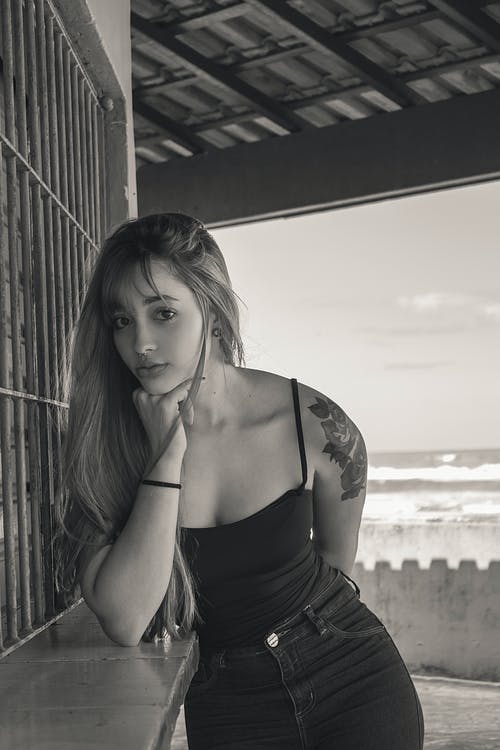 女人靠在灰色的表面上的灰度摄影 · 免费素材图片