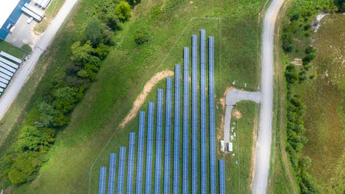 太阳能电池板阵列在绿色草地上的鸟瞰图 · 免费素材图片