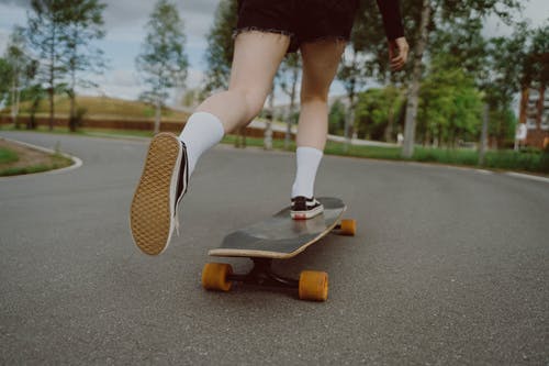 白袜子和白鞋骑在黑色滑板上的女人 · 免费素材图片