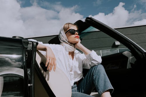 白色长袖衬衫和蓝色牛仔牛仔裤，坐在车上的女人 · 免费素材图片