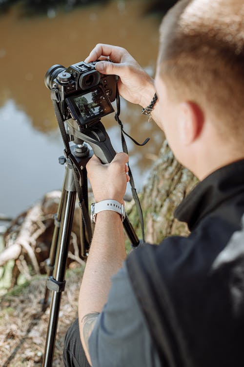 拿着黑单反相机的黑色衬衫的男人 · 免费素材图片