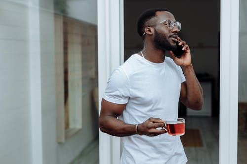 从红色陶瓷杯喝水的白船员脖子t恤的男人 · 免费素材图片