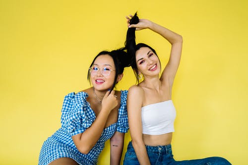 2名妇女微笑着站在黄墙旁 · 免费素材图片