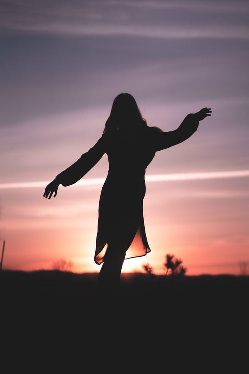 女人在日落时举手的剪影 · 免费素材图片