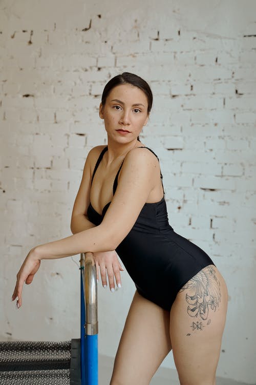 黑色背心和黑色短裤坐在不锈钢栏杆上的女人 · 免费素材图片