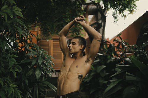 黑色短裤站在绿树旁的裸照人 · 免费素材图片