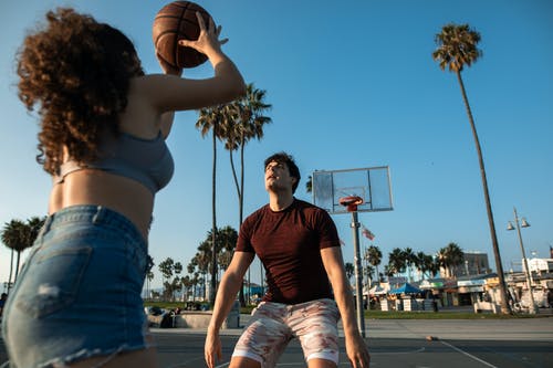 黑色背心和蓝色牛仔短裤的男人抱着篮球 · 免费素材图片
