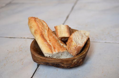 棕色木制圆形托盘上的黑面包 · 免费素材图片