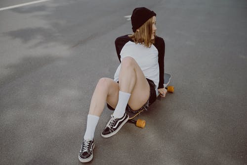 白衬衫和黑色短裤坐在灰色的水泥地板上的女人 · 免费素材图片
