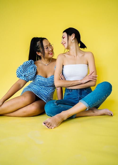 2名妇女坐在黄色的地板上 · 免费素材图片
