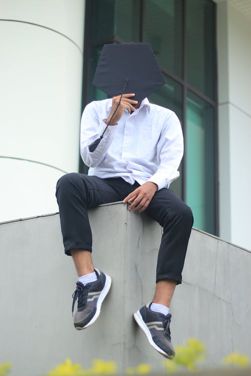 白色礼服衬衫和黑色的裤子，坐在白色的混凝土墙上的男人 · 免费素材图片