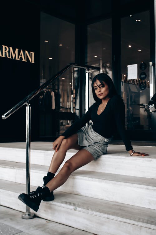 黑色衬衫和白色短裤坐在地板上的女人 · 免费素材图片