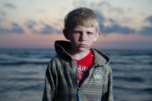 站在水边的蓝色和白色格子连帽衫的男孩 · 免费素材图片