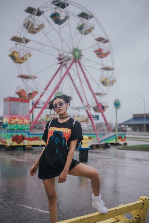 黑船员的脖子t恤和蓝色的牛仔短裤，坐在水泥地上的女人 · 免费素材图片