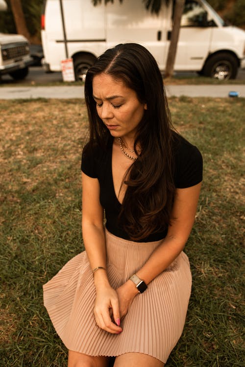 坐在绿草地上的黑色衬衫的女人 · 免费素材图片
