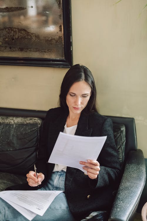 拿着白色打印机纸的黑色长袖衬衫的女人 · 免费素材图片