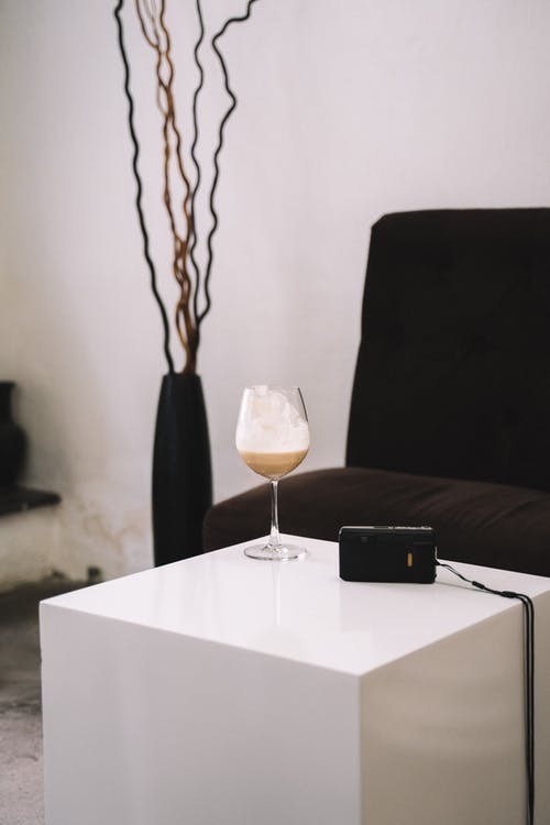 白色桌上的透明酒杯旁边的黑色遥控器 · 免费素材图片