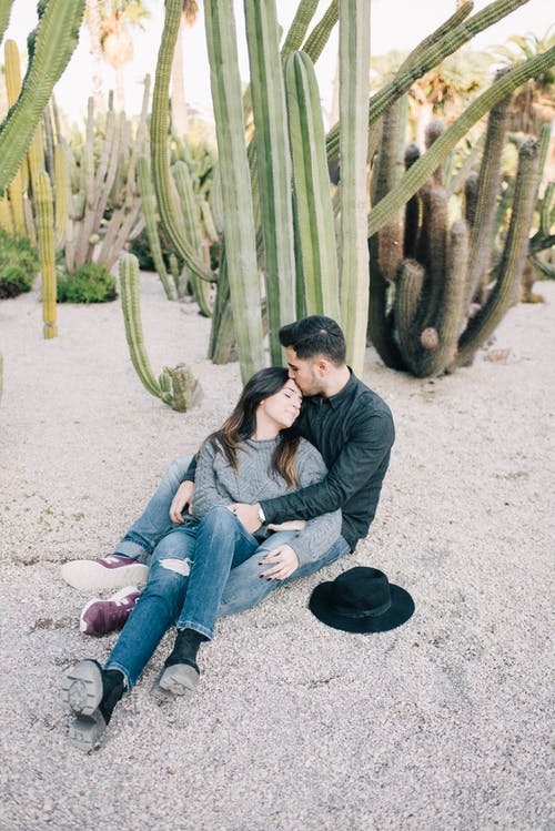 男人和女人坐在灰色的沙滩上 · 免费素材图片