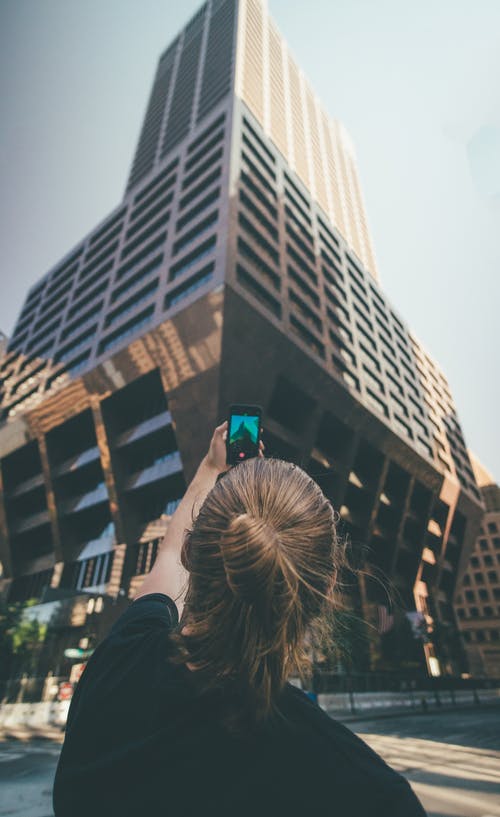 女人白天拍摄的高层建筑的照片 · 免费素材图片