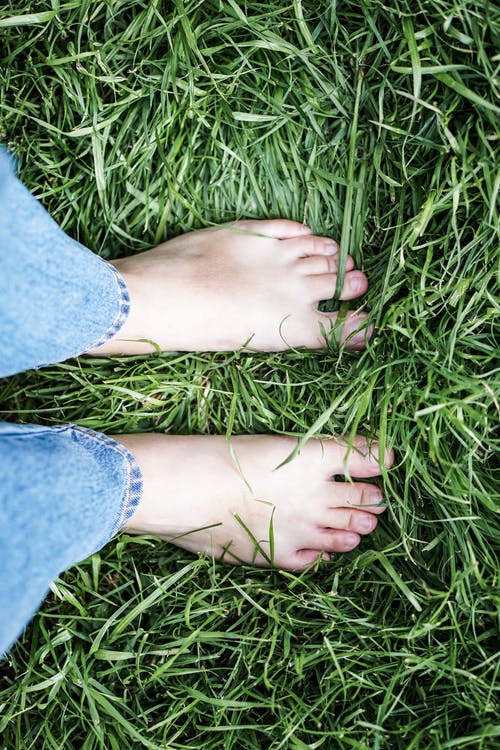 穿着蓝色牛仔牛仔裤，站在绿色的草地上的人 · 免费素材图片