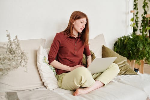棕色长袖衬衫坐在白色的床上的女人 · 免费素材图片