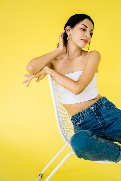 白色背心和蓝色牛仔短裤，坐在黄色的椅子上的女人 · 免费素材图片