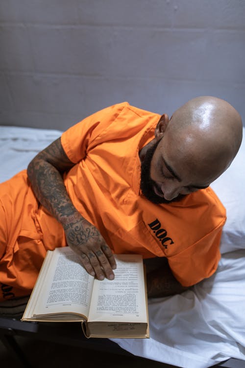 橙色衬衫阅读书中的男人 · 免费素材图片