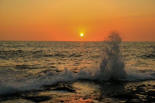 有关日落, 橘色天空, 波浪撞擊的免费素材图片