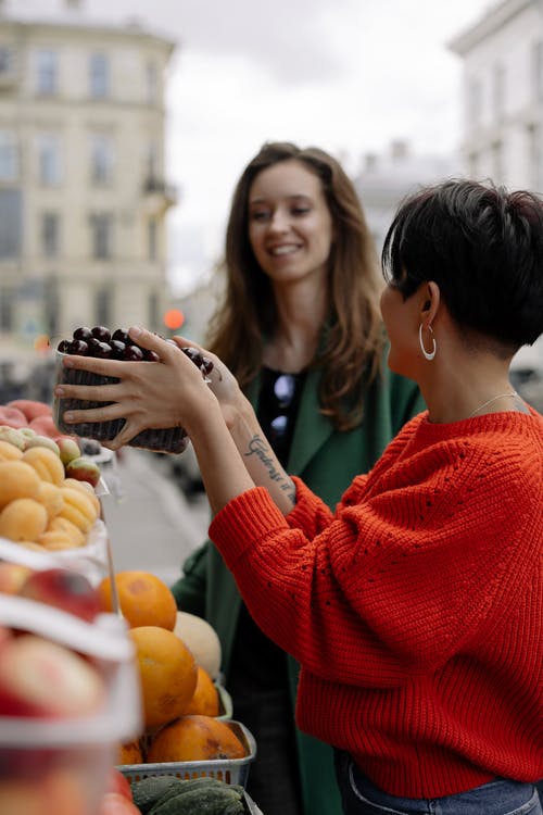 拿着橙色果子的红色毛线衣的妇女 · 免费素材图片