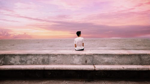 坐在海边的混凝土平台上的人的照片 · 免费素材图片