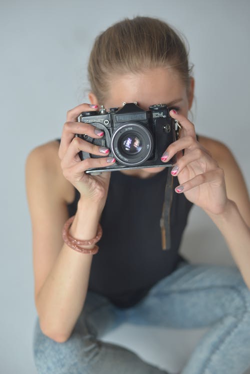 拿着黑色的数码单反相机的蓝色牛仔夹克的女人 · 免费素材图片
