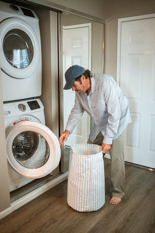 站在白色的前负荷洗衣机旁边的白色礼服衬衫的男人 · 免费素材图片