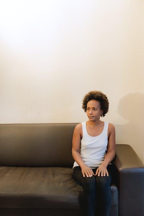 白色背心坐在灰色的沙发上的女人 · 免费素材图片