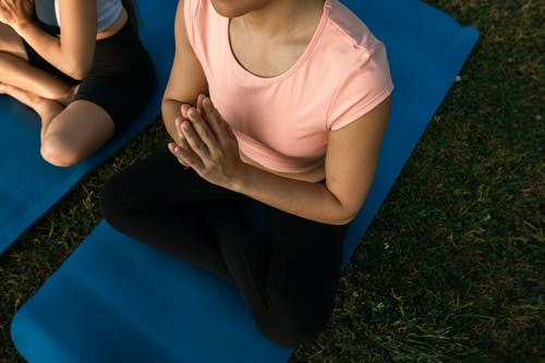 粉红色的背心和黑色的裤子，坐在蓝色纺织上的女人 · 免费素材图片