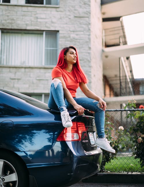 女人穿着红色圆领衬衫和蓝色褪色的牛仔裤 · 免费素材图片