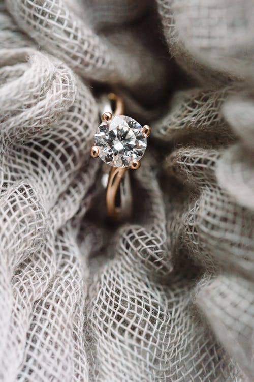 白色纺织品上的金银钻石戒指 · 免费素材图片