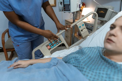 蓝色的衬衫和灰色的裤子，站在医院的床上的人 · 免费素材图片