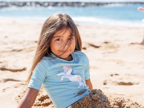 坐在海边的棕色岩石上的蓝色船员脖子t恤的女孩 · 免费素材图片
