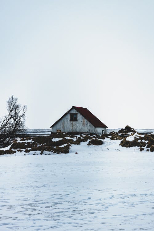 天空下的大海附近的雪地上的老房子 · 免费素材图片