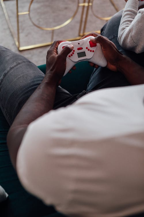 拿着白色和红色塑料玩具的白衬衫和蓝色牛仔牛仔裤的人 · 免费素材图片