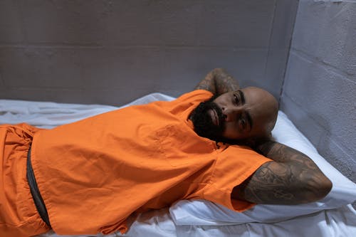 躺在床上的橙色polo衫的男人 · 免费素材图片