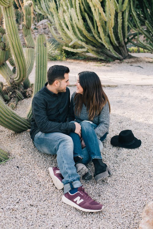 男人和女人坐在灰色的沙滩上 · 免费素材图片