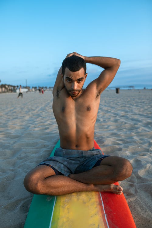 坐在白色的沙滩上的蓝色短裤的裸照人 · 免费素材图片