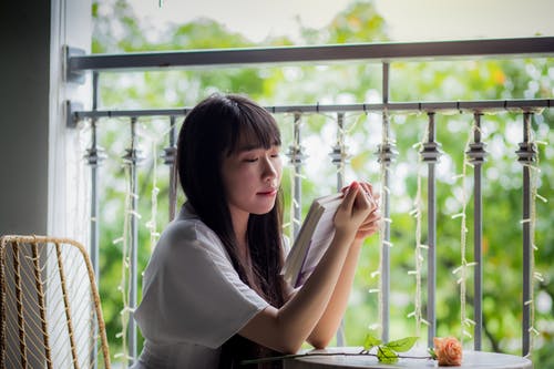 坐着的女人看书的选择性焦点摄影 · 免费素材图片