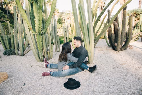 男人和女人坐在灰色的水泥地板上 · 免费素材图片