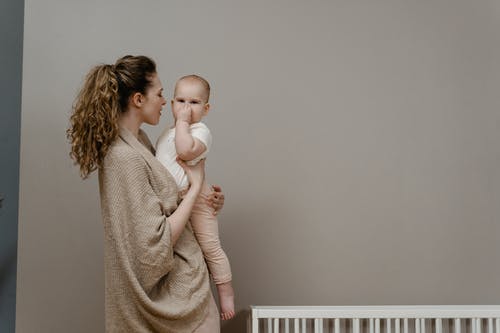 抱着宝宝穿白衬衣的棕色毛衣的女人 · 免费素材图片