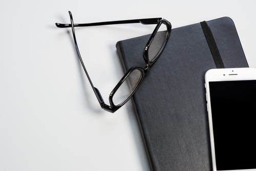 黑框眼镜，笔记本和智能手机 · 免费素材图片