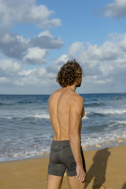 黑色短裤站在海滩上的裸照人 · 免费素材图片