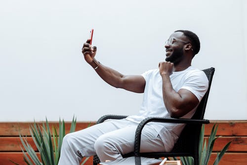 坐在黑色金属长凳上的白船员脖子t恤的男人 · 免费素材图片